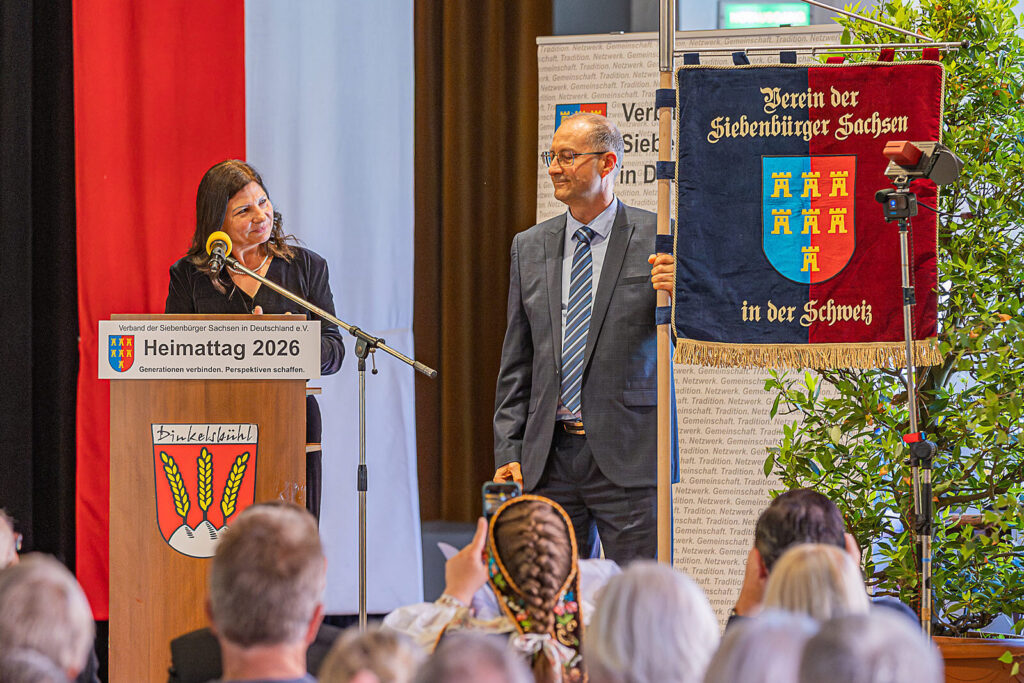 Marianne Hallmen und Franz Both, Co-Vorsitzende des Vereins der Siebenbürger Sachsen in der Schweiz, bedanken sich für den Beitritt und präsentieren ihre Vereinsfahne.